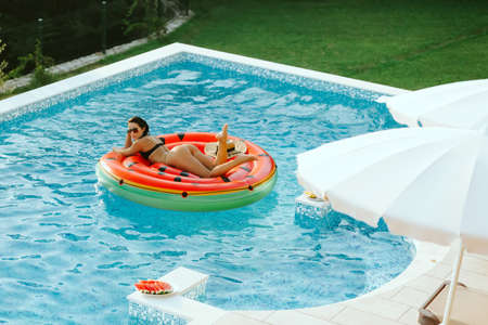 woman relax in swimming pool at sunset outdoorsの写真素材