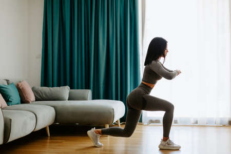 Athletic woman legs lunges workout at home, squats. Home workout.の写真素材