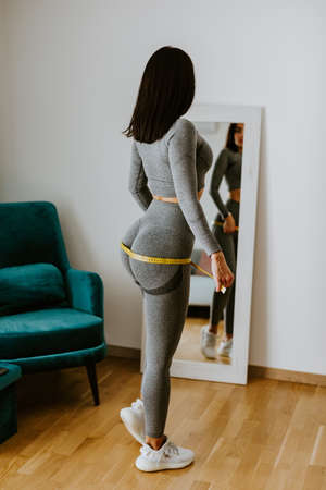 Fitness Woman Measuring buttocks With Tape at home. strong buttocks.の写真素材
