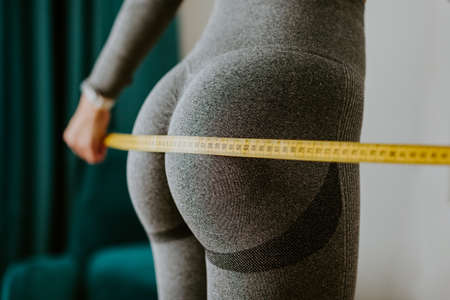 Fitness Woman Measuring butt With Tape at home. strong buttocks concept.の写真素材