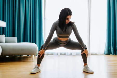 Young attractive woman practicing yoga at home. Legs stretching practiceの写真素材