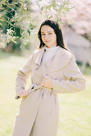 outdoor lifestyle fashion portrait of young woman wearing spring coatの写真素材