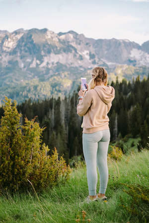Hipster girl is shooting video of beautiful landscape on smartphoneの写真素材