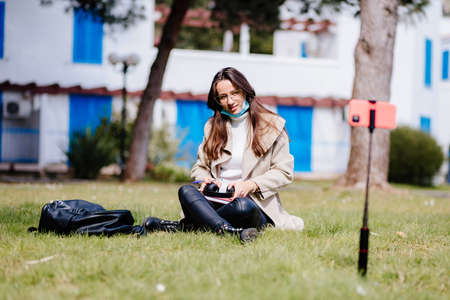 female student virtual learning on mobile wearing face mask internet outdoorsの写真素材