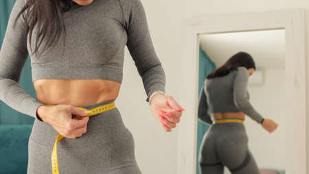 slim Woman waist Measuring With Tape at homeの写真素材