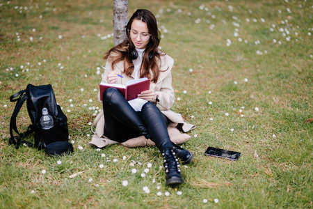 female student virtual learning on mobile outdoors sitting in park