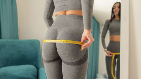 Fitness Woman Measuring butt With Tape at home. strong buttocks concept.の写真素材