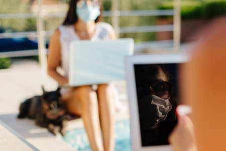 woman using laptop in face mask and chat with friendの写真素材