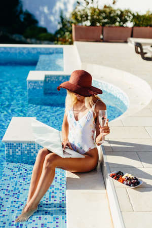 woman using laptop and work remotely near swimming poolの写真素材