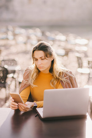 serious woman freelancer work on laptop outdoors in cafeの写真素材