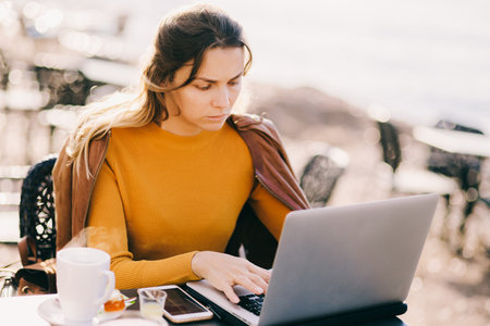 serious Female entrepreneur work on laptop outdoors in cafeの写真素材