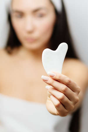 Woman using Gua Sha scraper over skinの写真素材