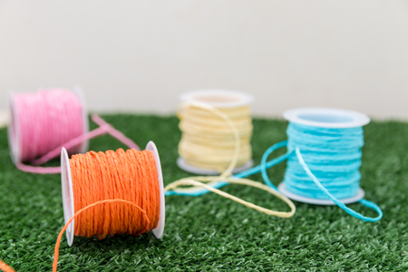 Four of colorful thread on grass with white background