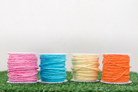 Four of colorful thread on grass with white backgroundの写真素材