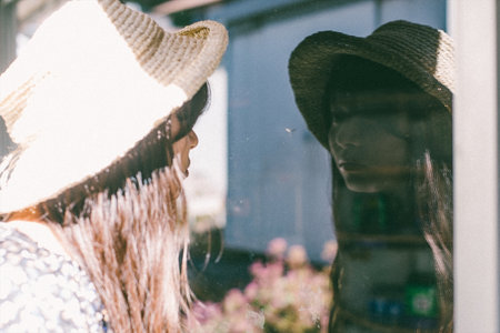 A woman in a straw hat looking at the figure on the glass