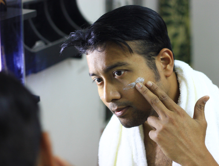 indian asian man looking after his appearance in front of a mirror beauty styling lifestyleの写真素材