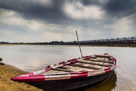 HDR landscape of a boar tied at the corner of river bed sandy beach and cloudy sky day time scene.の写真素材
