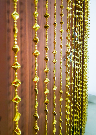 golden chimes decorating door curtain suspended and shallow depth of fieldの写真素材