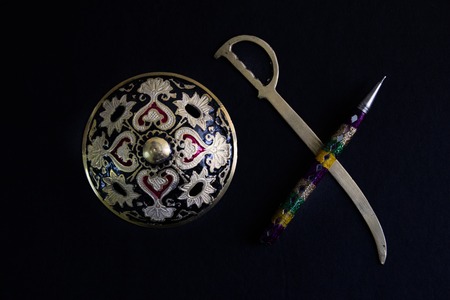 pen is mightier than sword concept by decorated round sword shield and pen in black background .antique artefactの写真素材