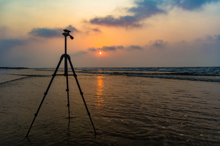 tripod in background of sunrise at sea beach for beach photography with space for text