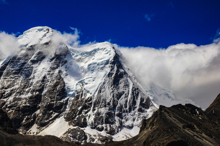 Landscape of deep blue sky and ice capped peaks of himalayan mountains with white clouds during day...