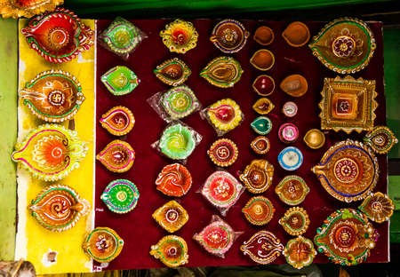 Different varieties of colourful diyas and diwali lamps for sale in a grocery shopの写真素材