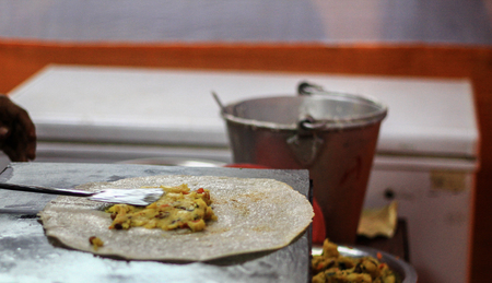 Adding potato masala to make masala dosa on a frying pan