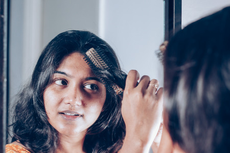 lady combing her hair with hairbrush at mirror.の写真素材