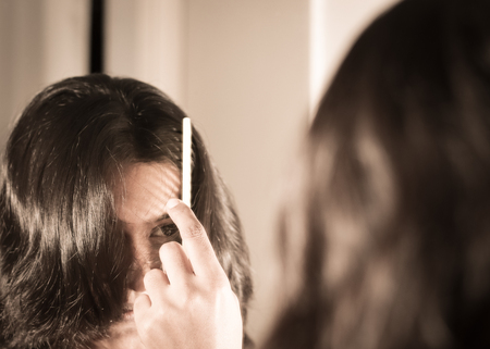 lady combing her hair looking at her image at mirror.の写真素材