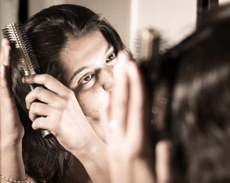 lady combing her hair with hairbrush at mirror.の写真素材