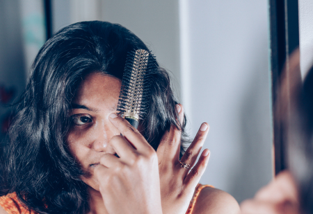 lady combing her hair with hairbrush at mirror.の写真素材