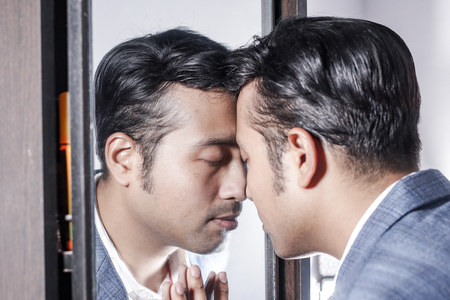 asian man in suit looking after his appearance in front of a mirror beauty styling lifestyle.