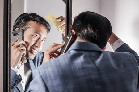asian man in suit looking after his appearance in front of a mirror beauty styling lifestyle.の写真素材