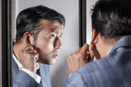 asian man in suit looking after his appearance in front of a mirror beauty styling lifestyle.の写真素材