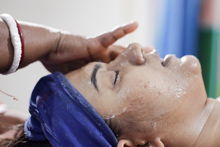 applying facial pack mask gel on face of a lady with hair band with eyes closed.side viewの写真素材