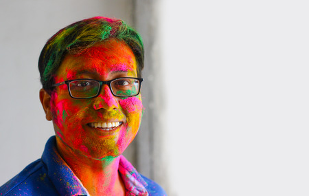 portrait of indian man face painted with colors smiling with eyes open space for textの写真素材
