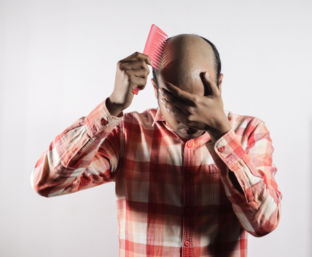 bald man covering his face in shame in white background with space for textの写真素材