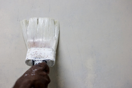 painting white paint on a wall with a paint brush with space for textの写真素材