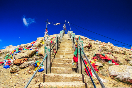steep rock stairs with colourful flags rising up with deep blue skyの写真素材