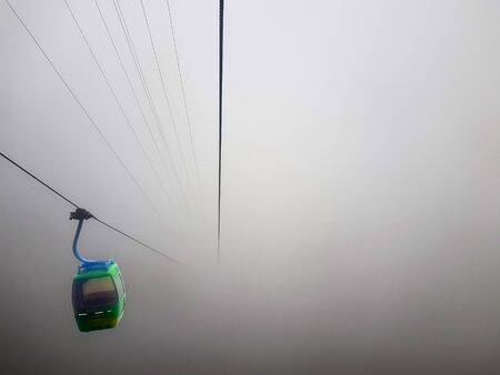 a cable car suspended in a cable in a very foggy weather with zero visibility