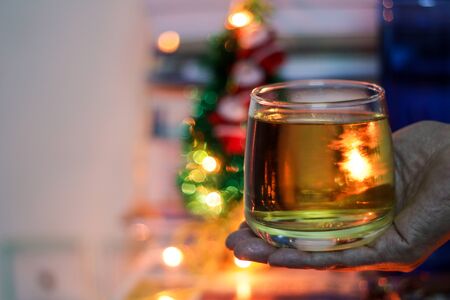 a glass of alcohol rum held in hand with background blurred bokeh lightsの写真素材