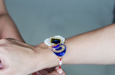 hand of a lady tying rakhi in hand of a guy during the hindu ritual of rakshabandhan with selective focusの写真素材