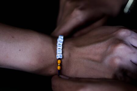 hand of a lady tying friendship band in hand of a guy with selective focusの写真素材