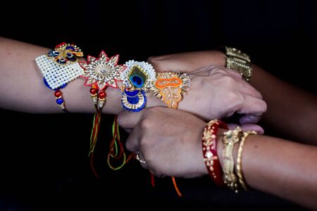 hand of a lady tying rakhi in hand of a guy during the hindu ritual of rakshabandhan with selective focusの写真素材