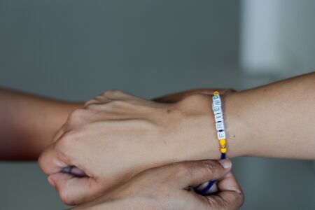 hand of a lady tying friendship band in hand of a guy with selective focusの写真素材