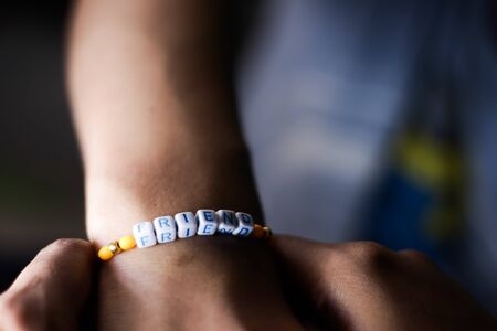 hand of a lady tying friendship band in hand of a guy with selective focus