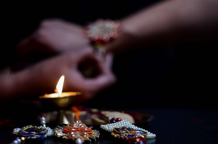 hand of a lady tying rakhi in hand of a guy during the hindu ritual of rakshabandhan with selective focusの写真素材