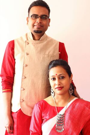a young indian bengali assamese married couple dressed in red and white ethnic indian dress