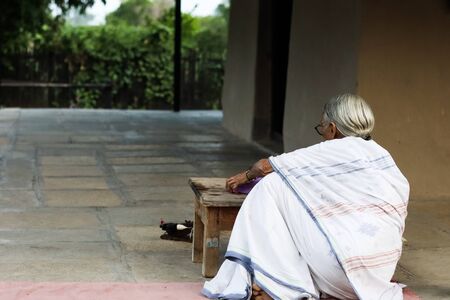 November 30, Maharashtra India,- An elderly lady in white dress reading books in the evening at Gandhi Ashram at Sevagram, Wardha. Mahatma Gandhi used to reside thereのeditorial素材