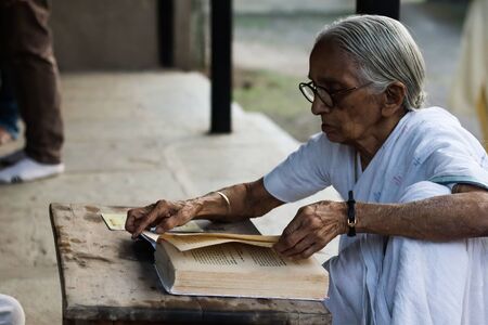 November 30, Maharashtra India,- An elderly lady in white dress reading books in the evening at Gandhi Ashram at Sevagram, Wardha. Mahatma Gandhi used to reside thereのeditorial素材